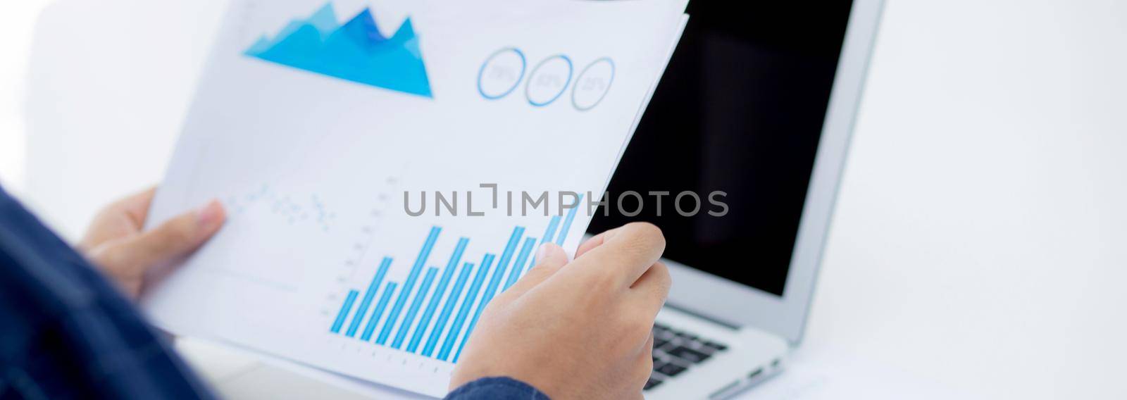 Hand of young business man looking document data graph and chart paper, marketing and investment, report of statistics profit for financial, economic and growth of finance, management and planning. by nnudoo