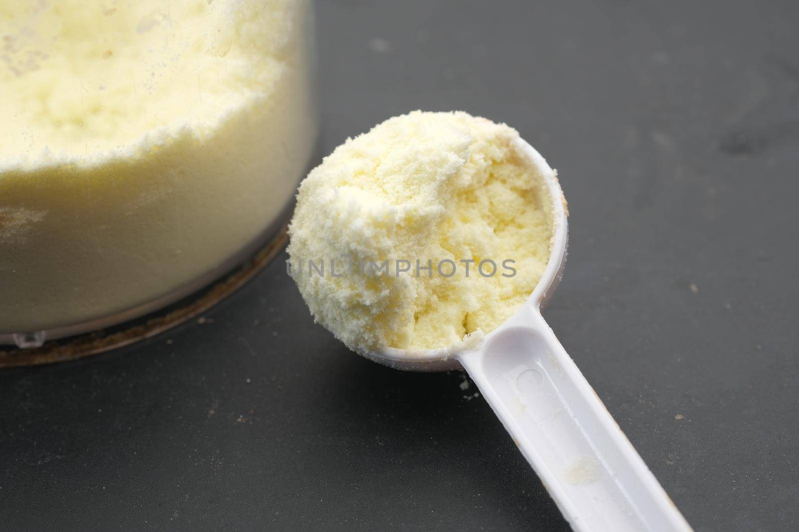 Close up of baby milk powder and spoon on tile background