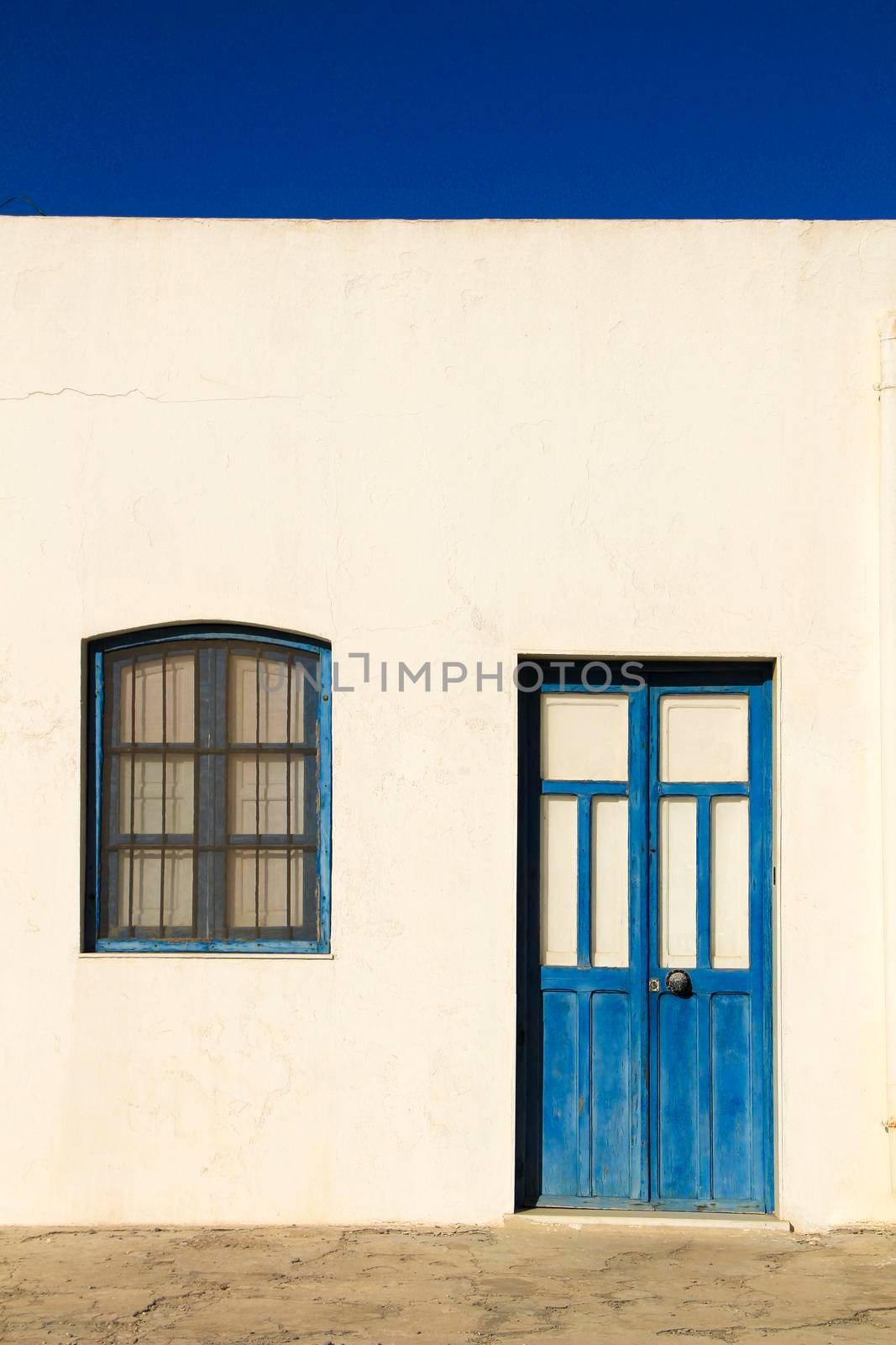 Typical Andalusian whitewashed facade with blue painted window and bench