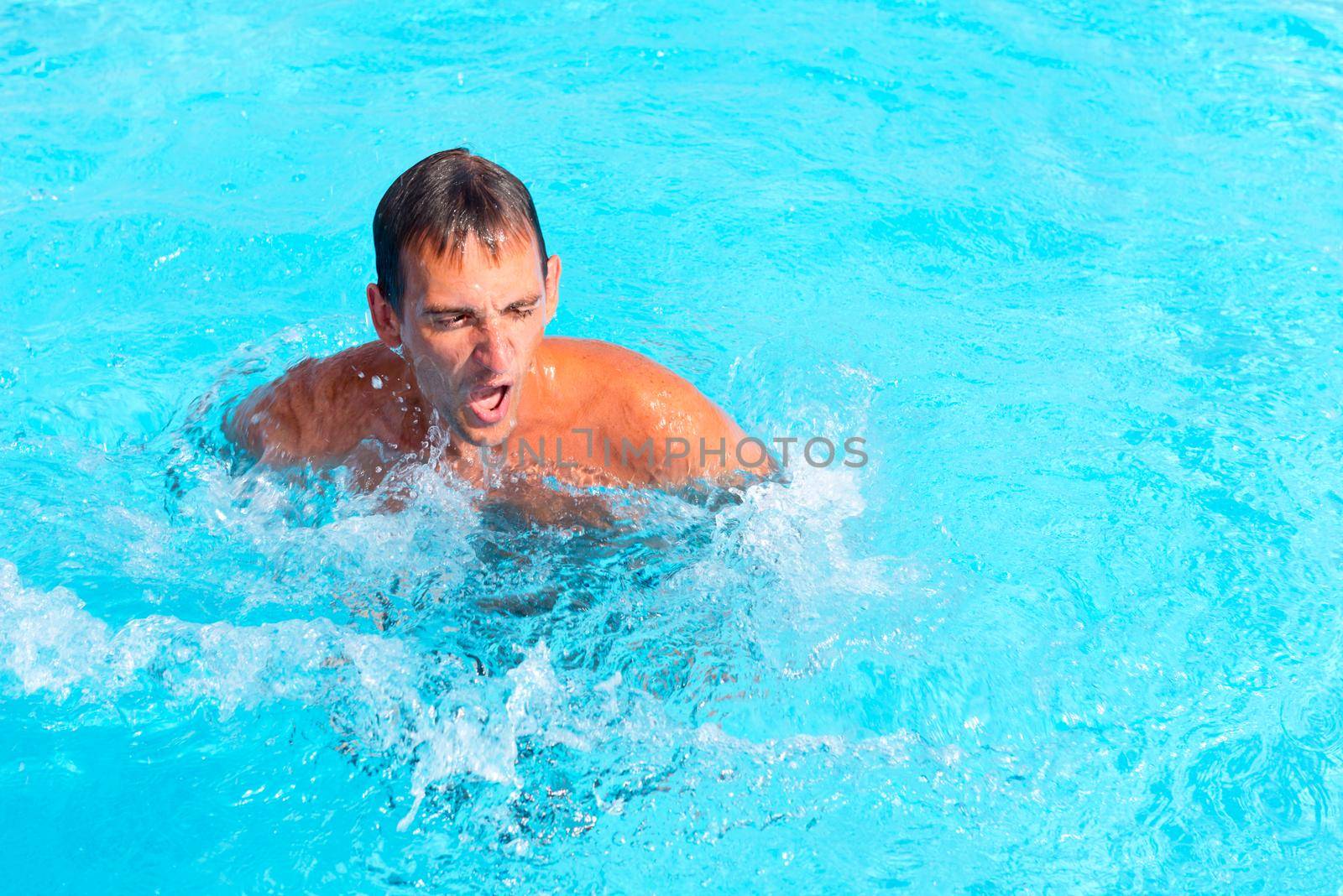 Young man swimming in the hotel pool