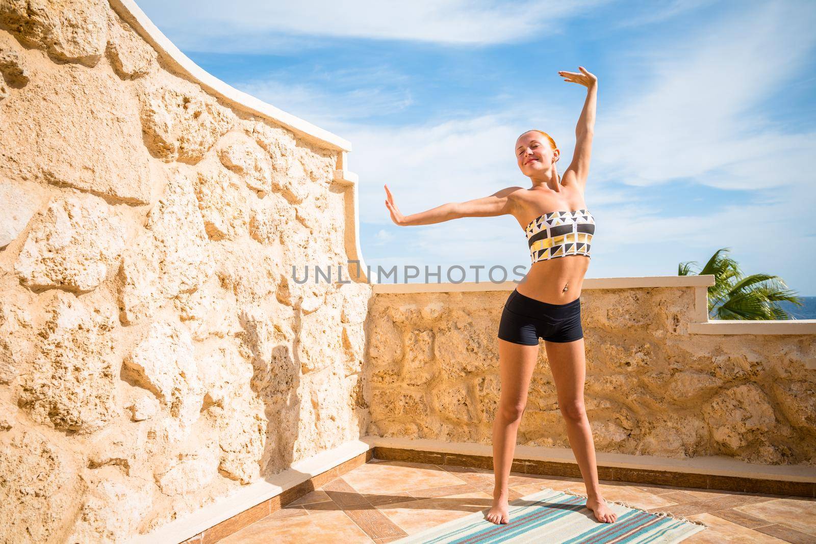 Beautiful woman practicing yoga outdoors against blue sky