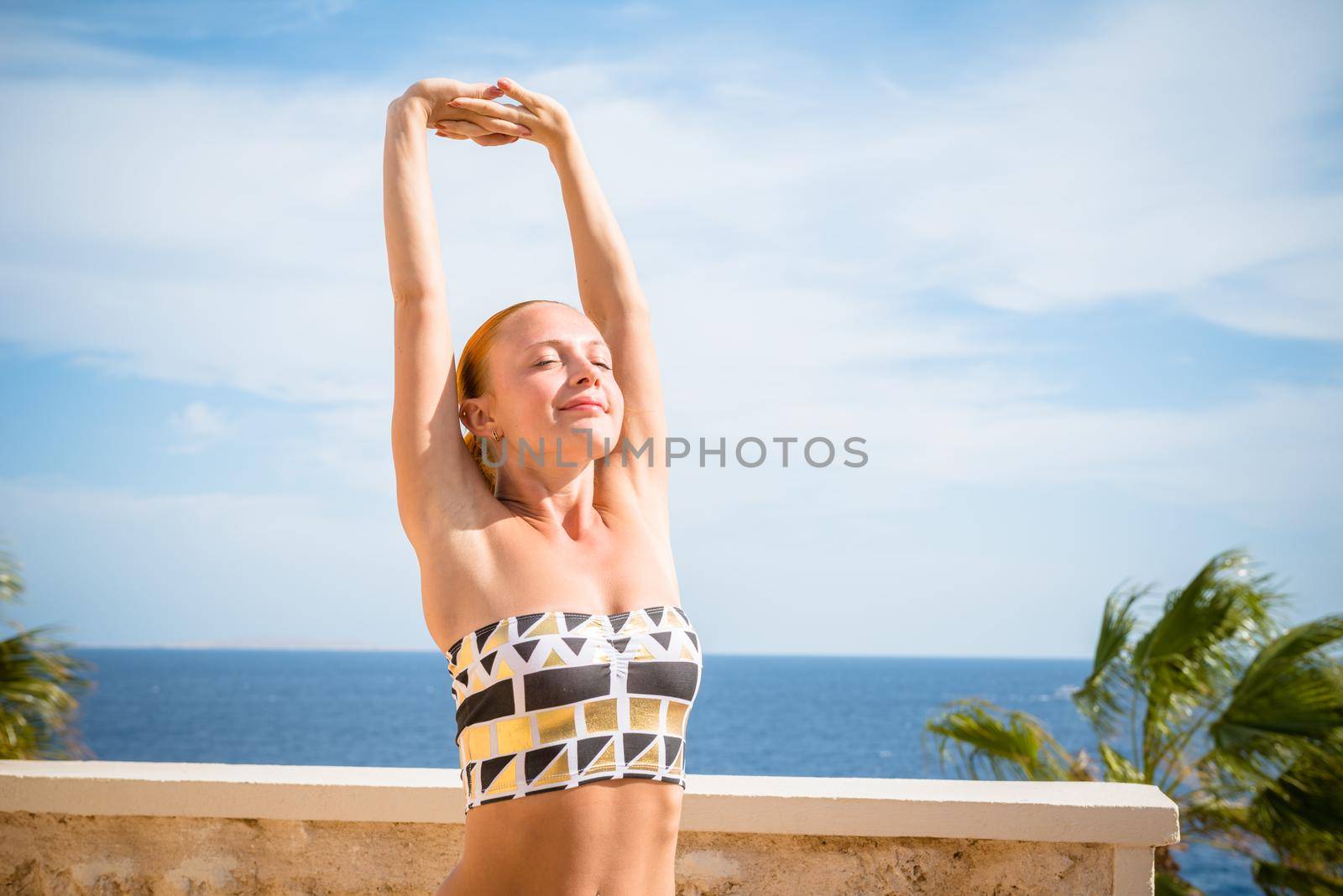 Beautiful woman practicing yoga outdoors against blue sky