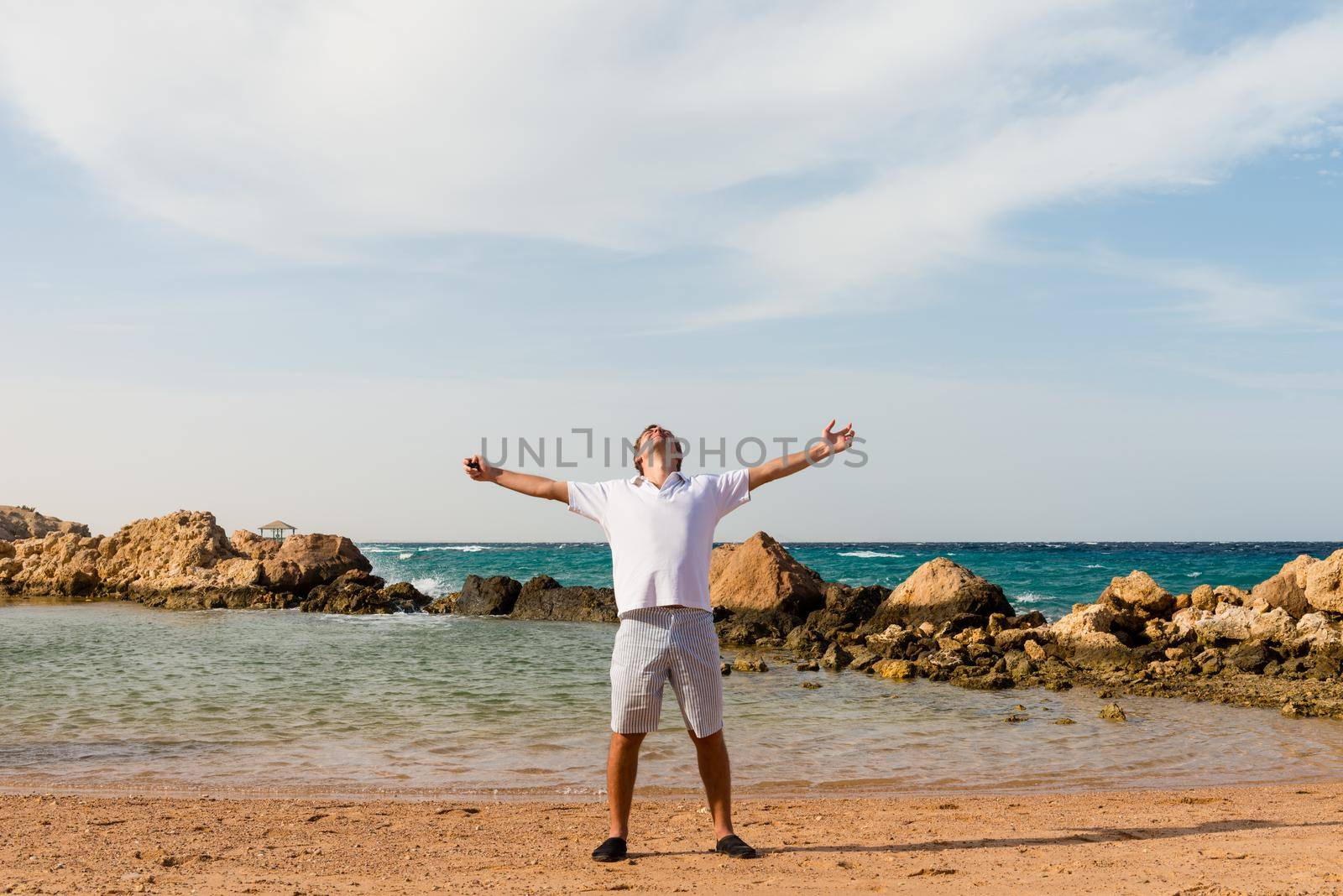 Happy young man with outstretched arms at the beach