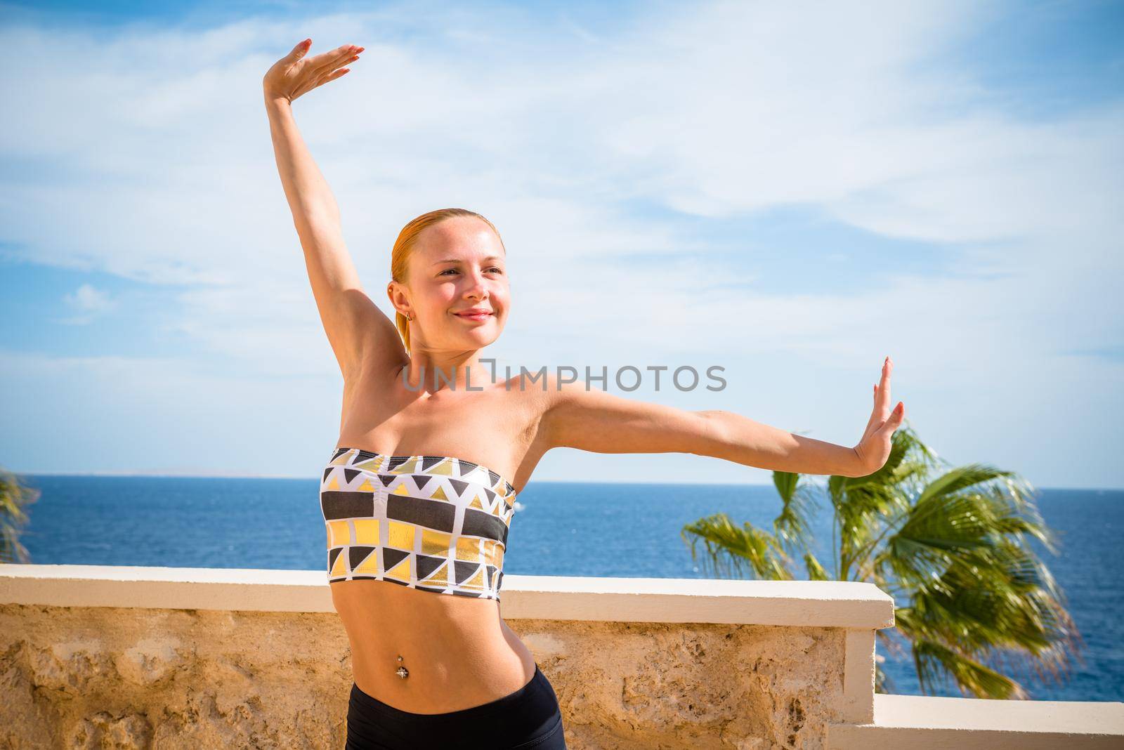 Beautiful woman practicing yoga outdoors against blue sky