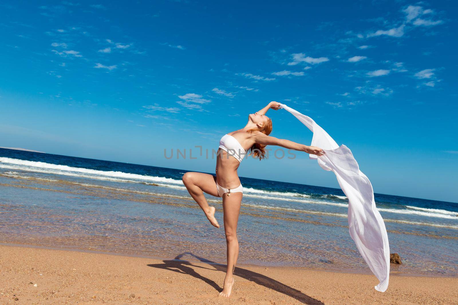 Carefree happy girl on the beach, fit sporty healthy sexy body in bikini, woman enjoys wind, freedom, vacation, summertime fun concept