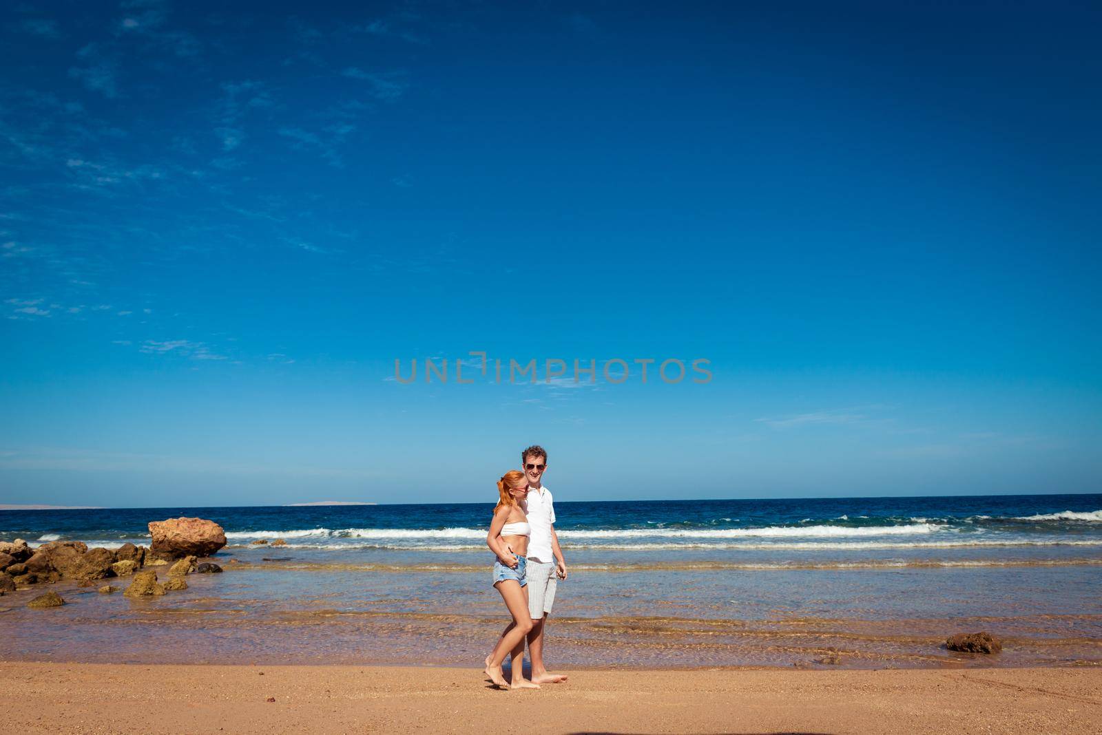 Romantic young couple walking on the beach with bare feet