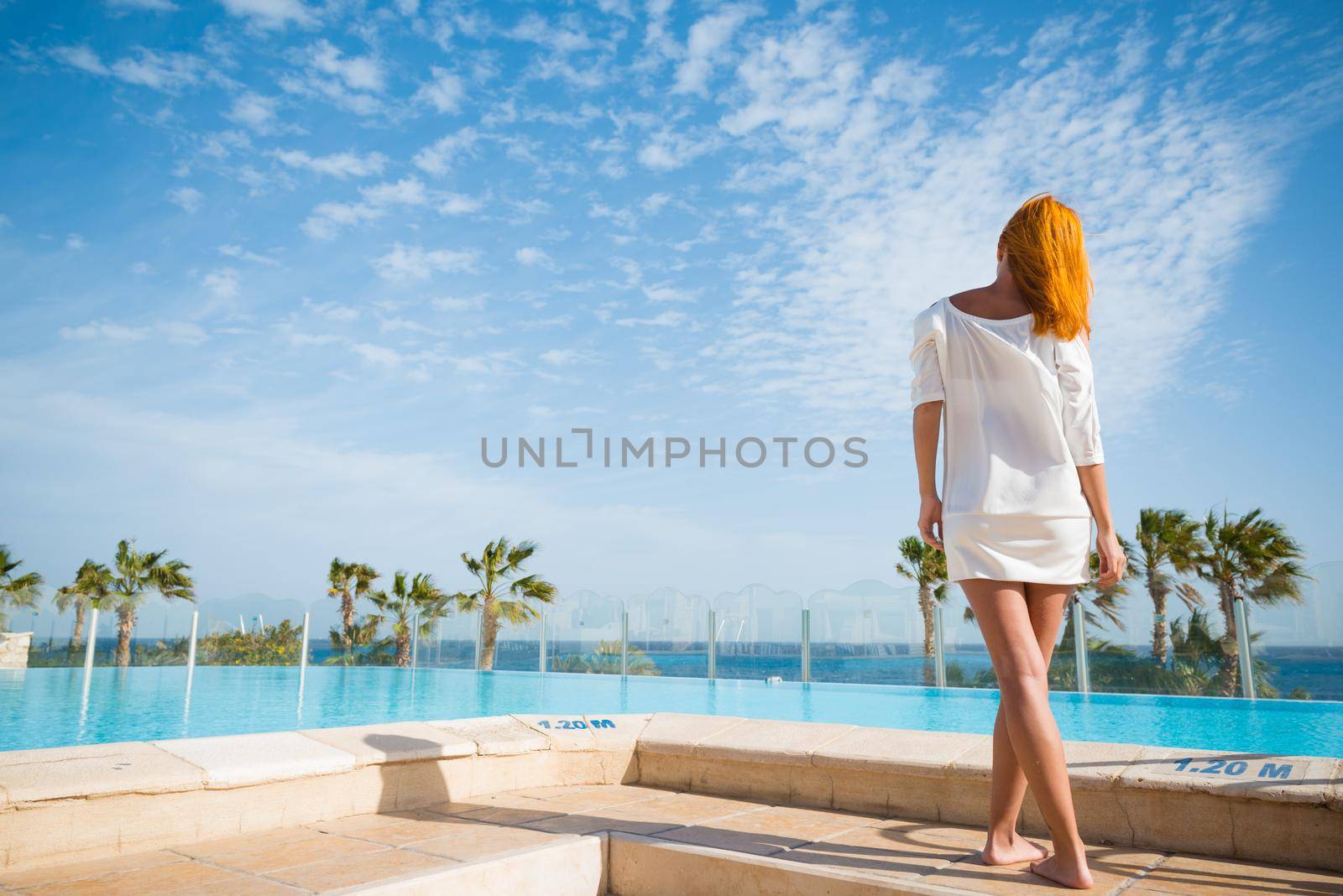 Young woman enjoying sun by pool at tourist resort