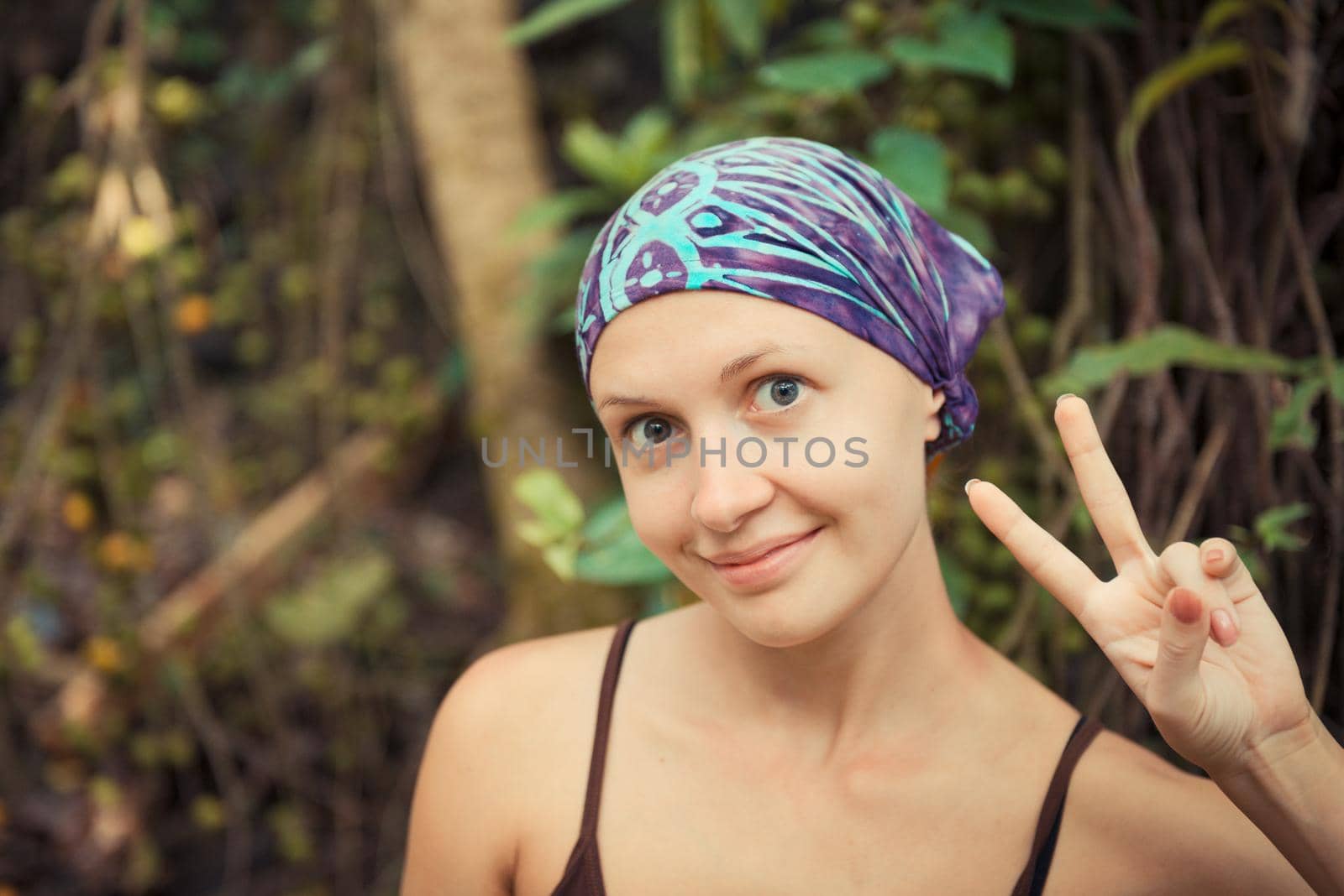 Young woman wearing do-rag showing victory sign
