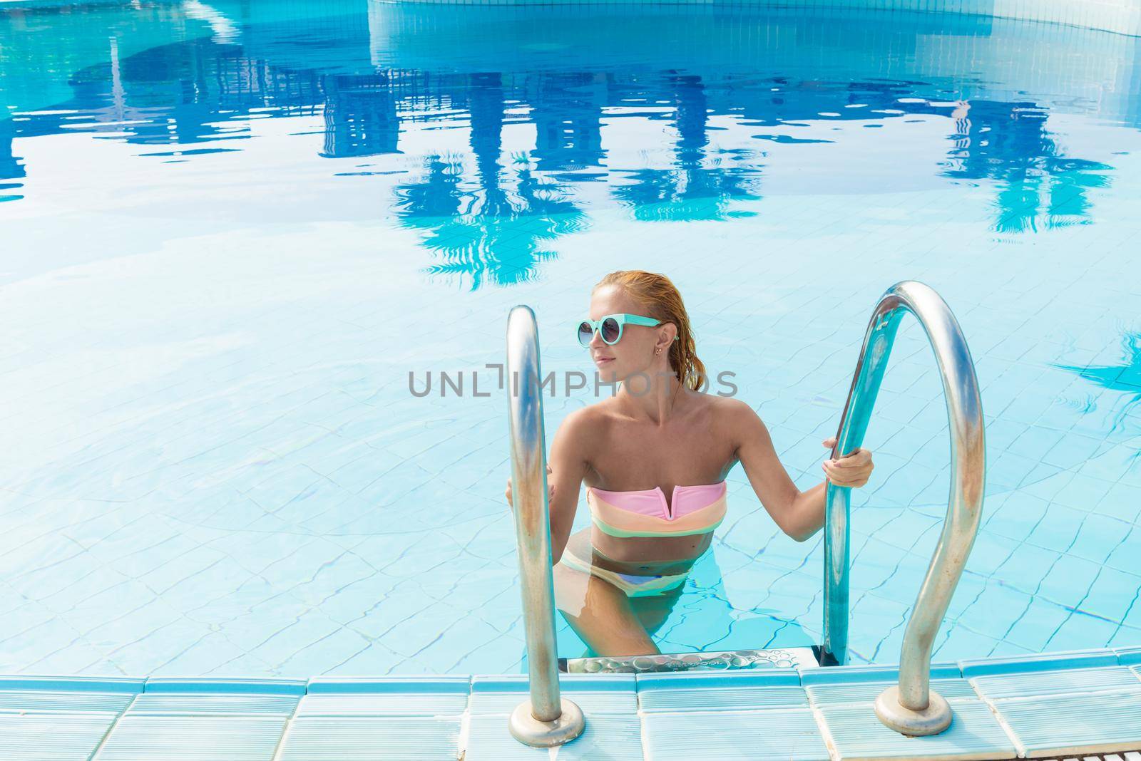 Beautiful young woman in swimming pool at tourist resort