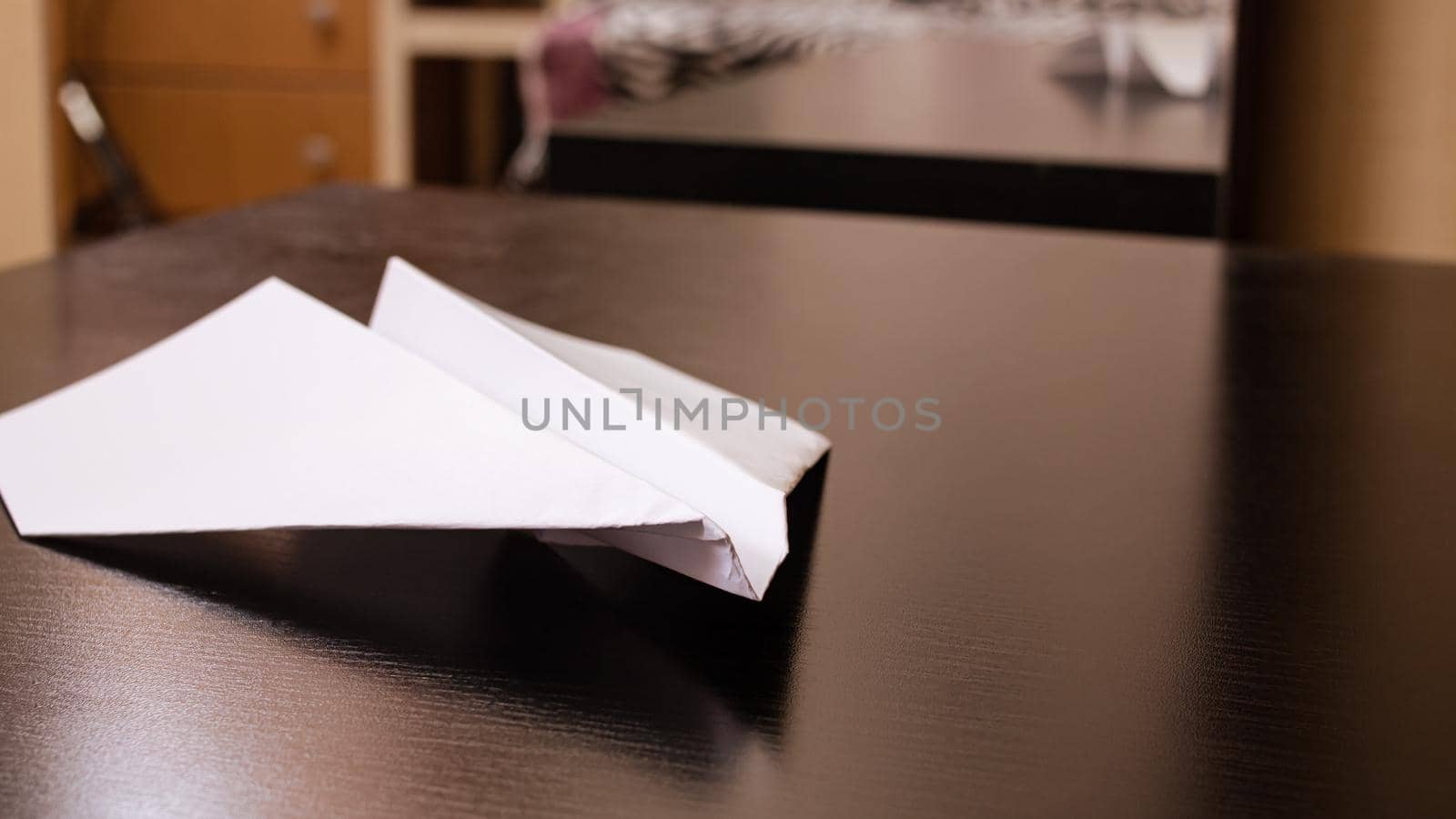 White paper plane on a black wooden table close up