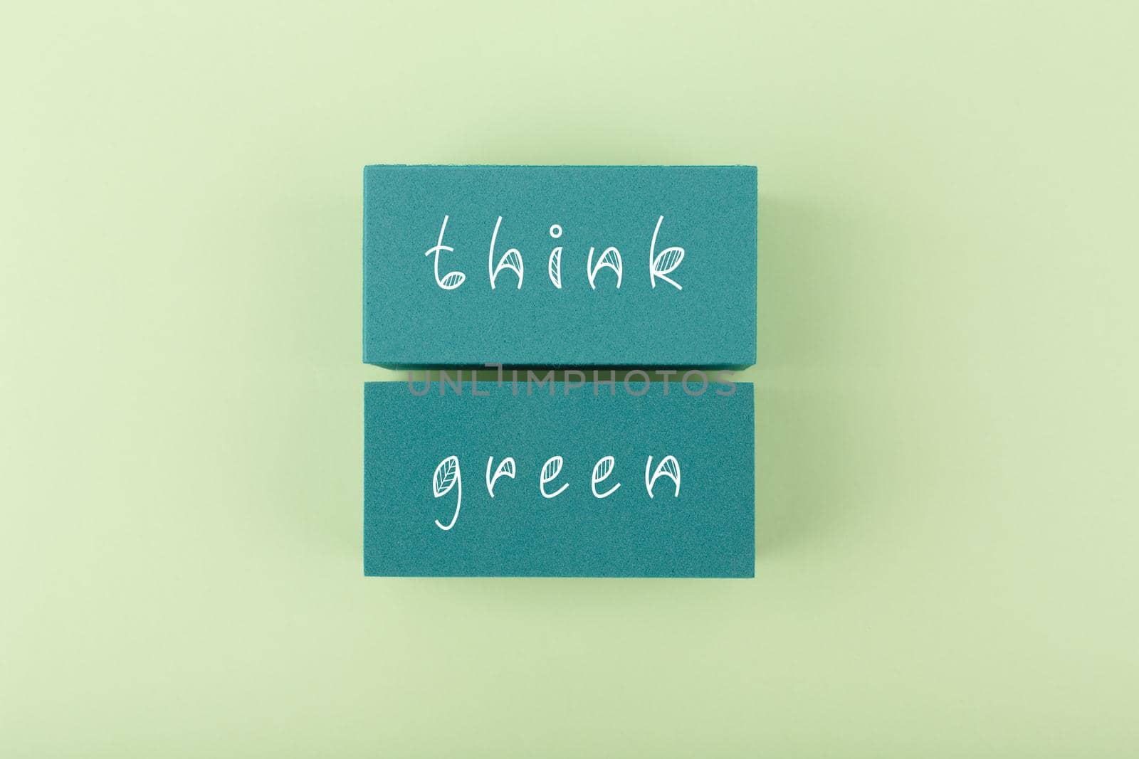 Modern minimal flat lay composition with think green inscription against bright green background. Concept of go green, recycle, reduce, reuse, zero waste and eco friendly lifestyle