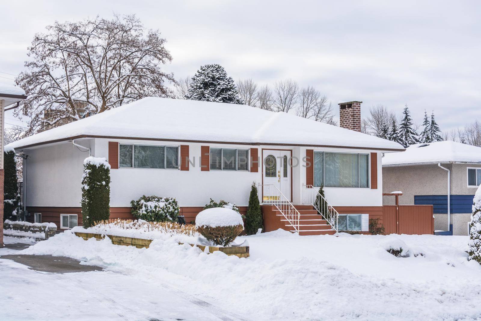 Family residential house with front yard in snow. North American house on winter cloudy day