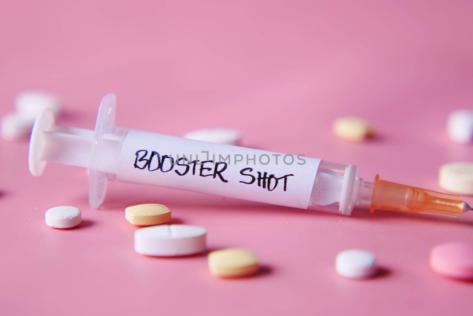booster shot test on syringe and pills on pink background, close up,