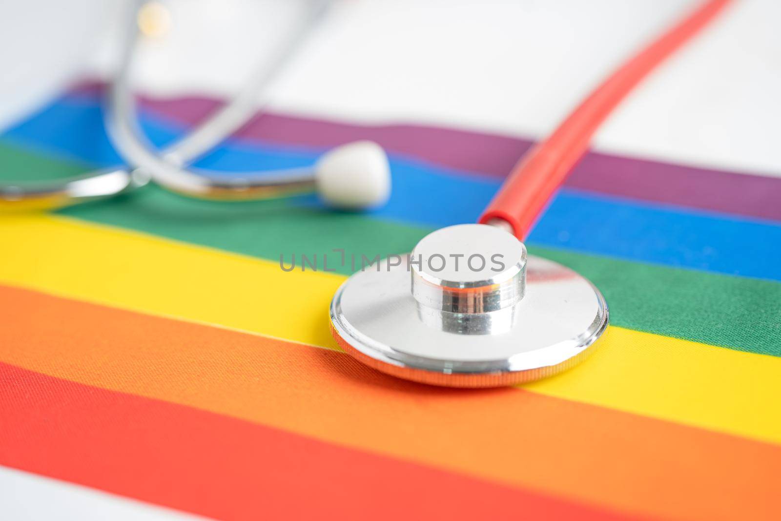 Red stethoscope on rainbow flag background, symbol of LGBT pride month celebrate annual in June social, symbol of gay, lesbian, bisexual, transgender, human rights and peace. by pamai