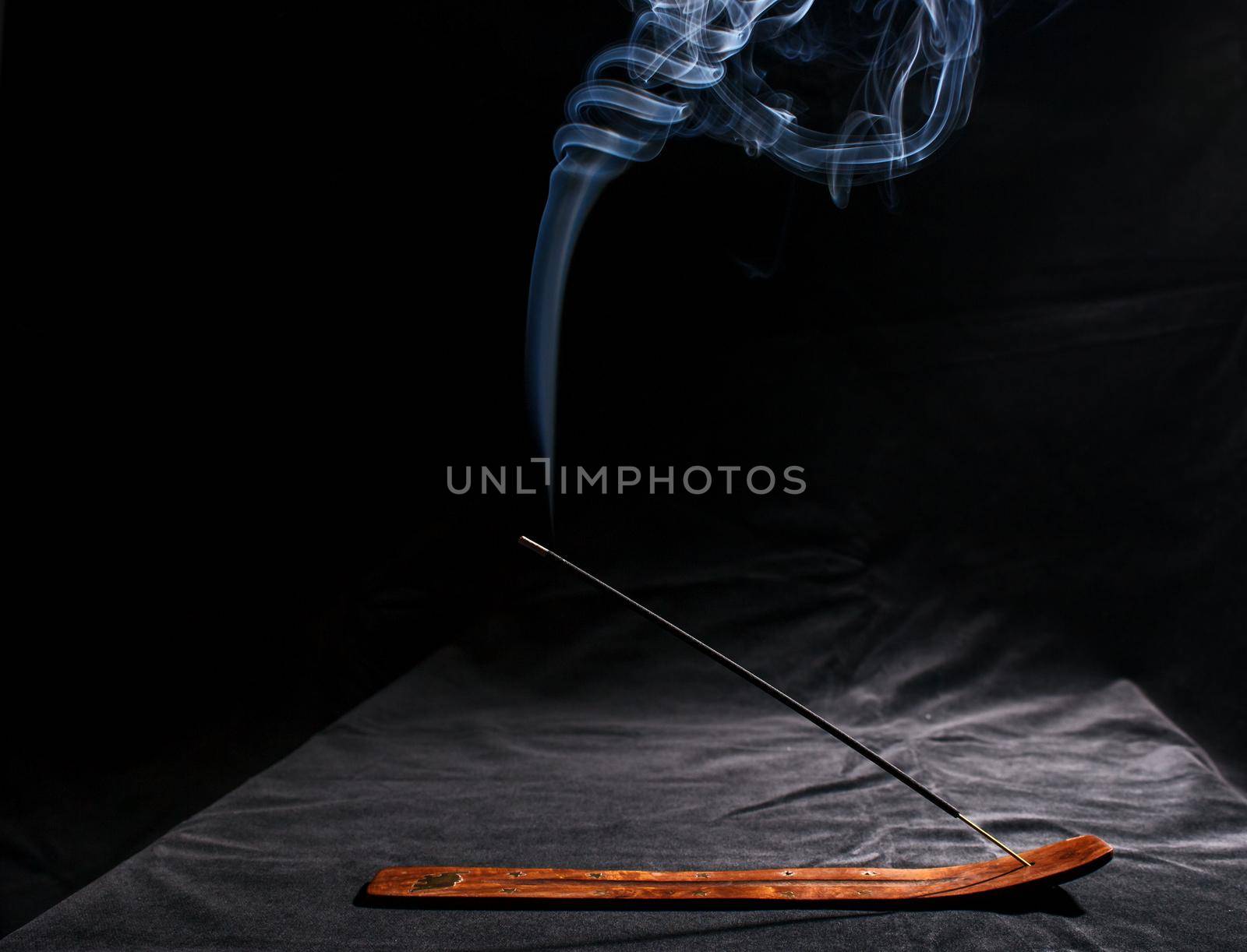 indian incense stick with smoke on black background indoor closeup