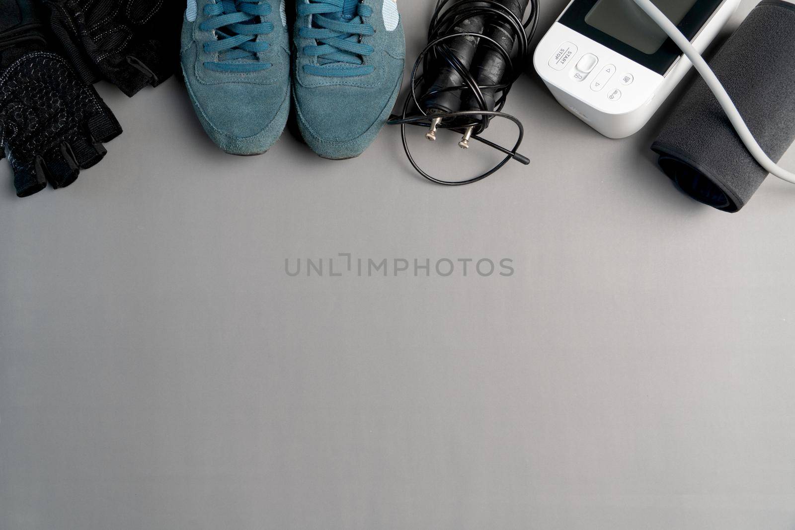 Healthy lifestyle. Jump rope  equipment and sphygmomanometer on a grey background. Top view with copy space.