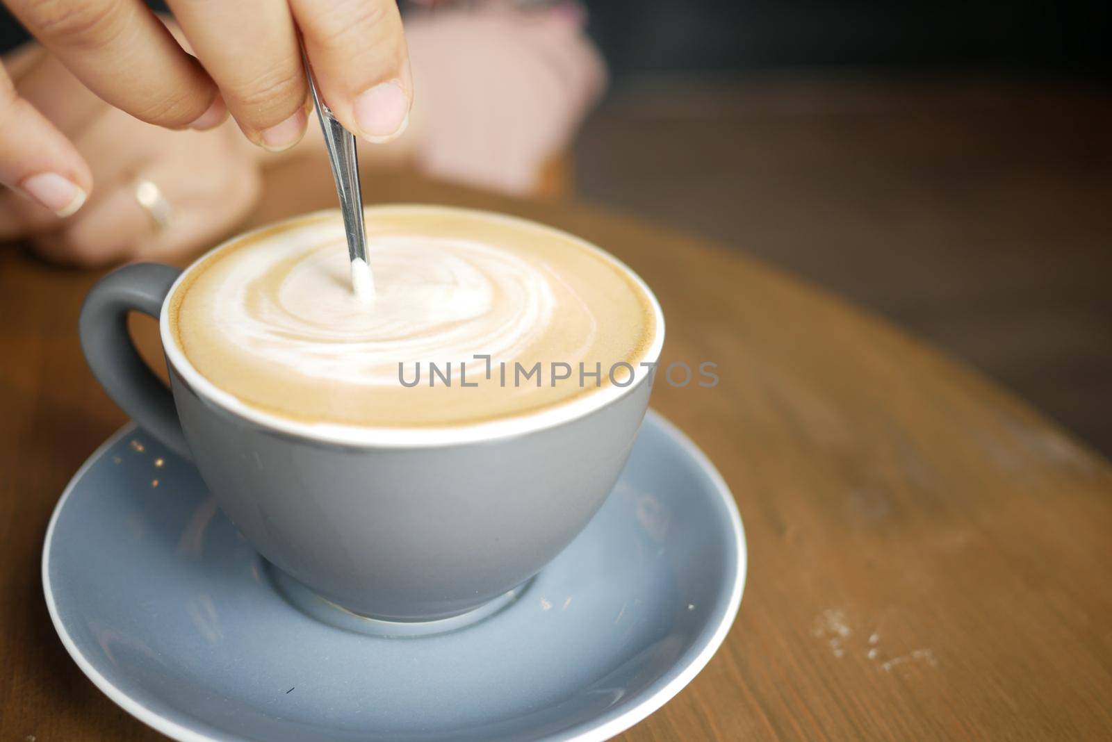 person hand stirring coffee with spoon
