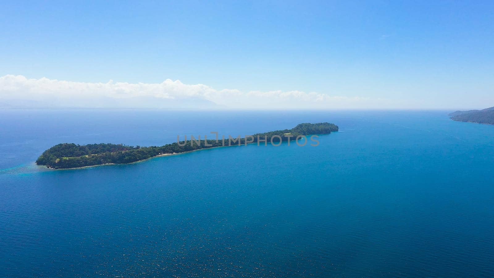 Top view of small tropical Big Liguid Island in the blue sea with a coral reef and the beach. Big Cruz Island, Philippines, Samal.