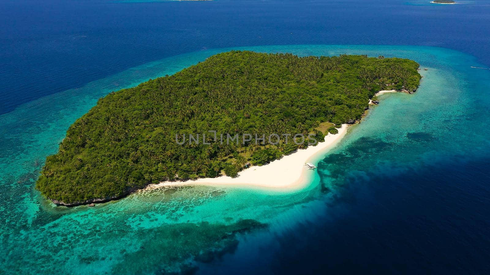 Atoll with a beautiful island, aerial view. White sand beach and blue sea. Mahaba Island, Philippines. Summer and travel vacation concept.