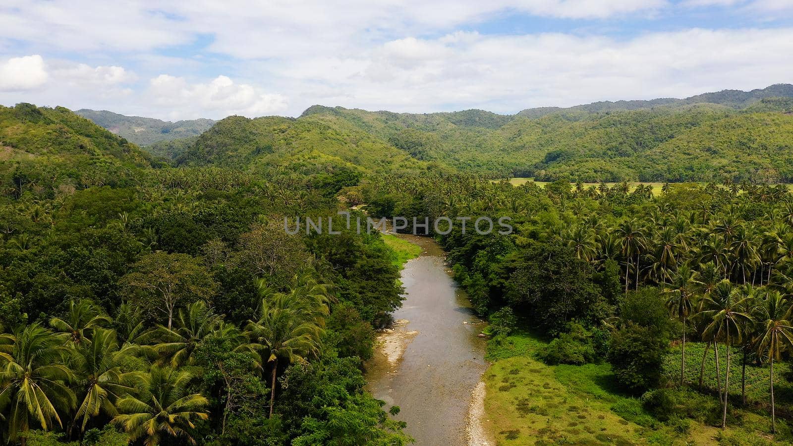 Mountain river on a tropical island, top view. Mountains and hills are covered with evergreen forest. Beautiful landscape in the Philippines. A river in the mountains on Leyte Island,