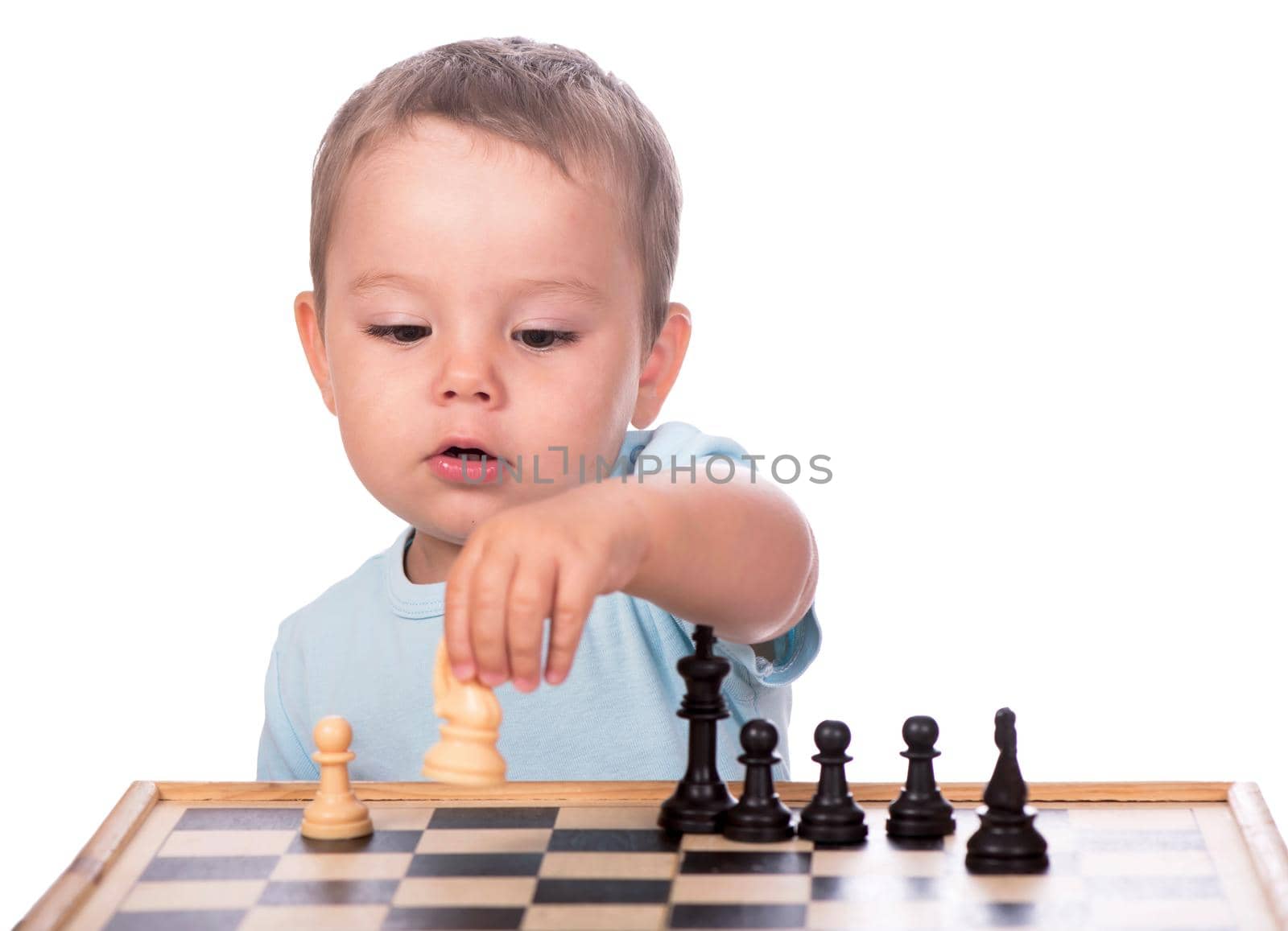 little boy staring at the chess pieces isolated on white background by aprilphoto