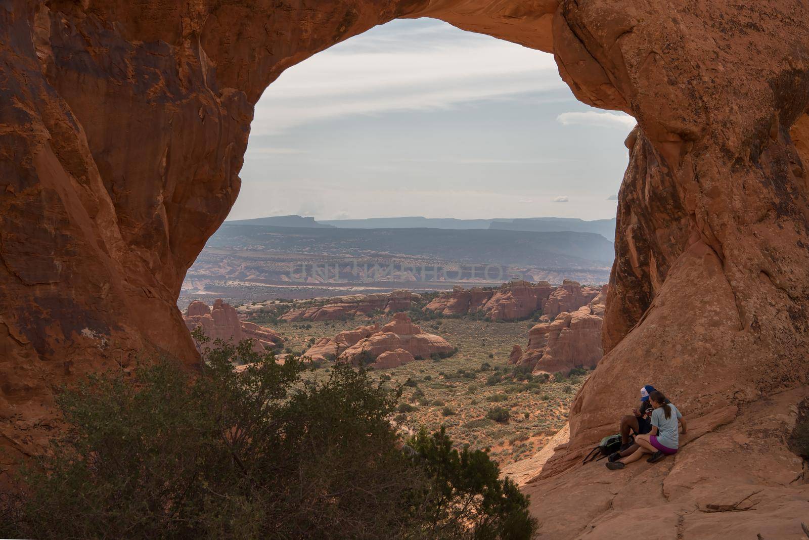 Utah Arches National Park the windows with girl and guy sitting together by jyurinko