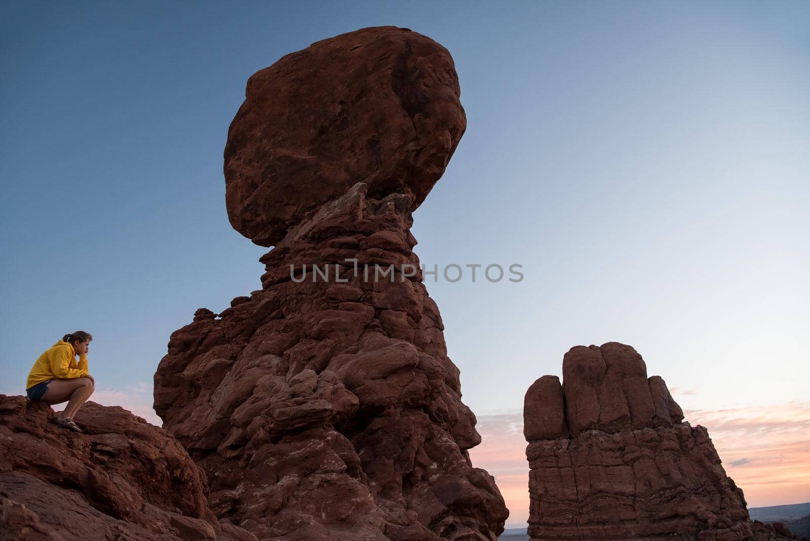 Arches National Park - Balanced Rock at sunset with girl pondering by jyurinko