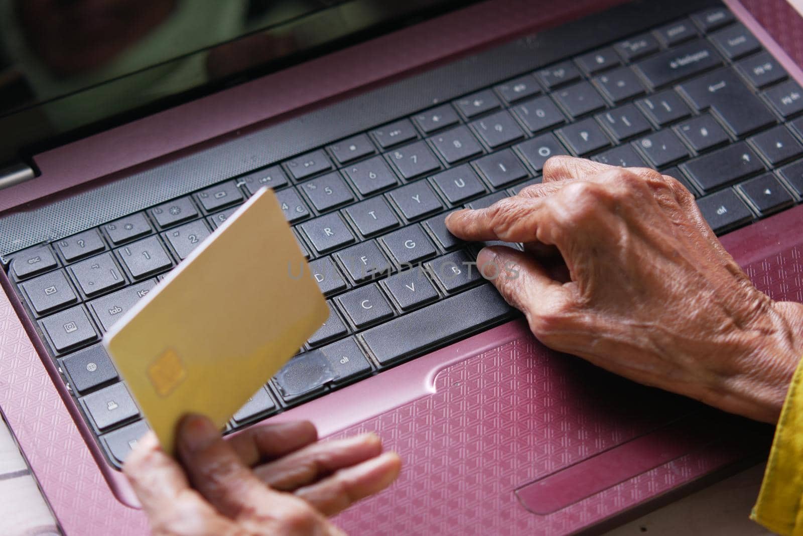 senior women hands holding credit card and using laptop shopping online by towfiq007