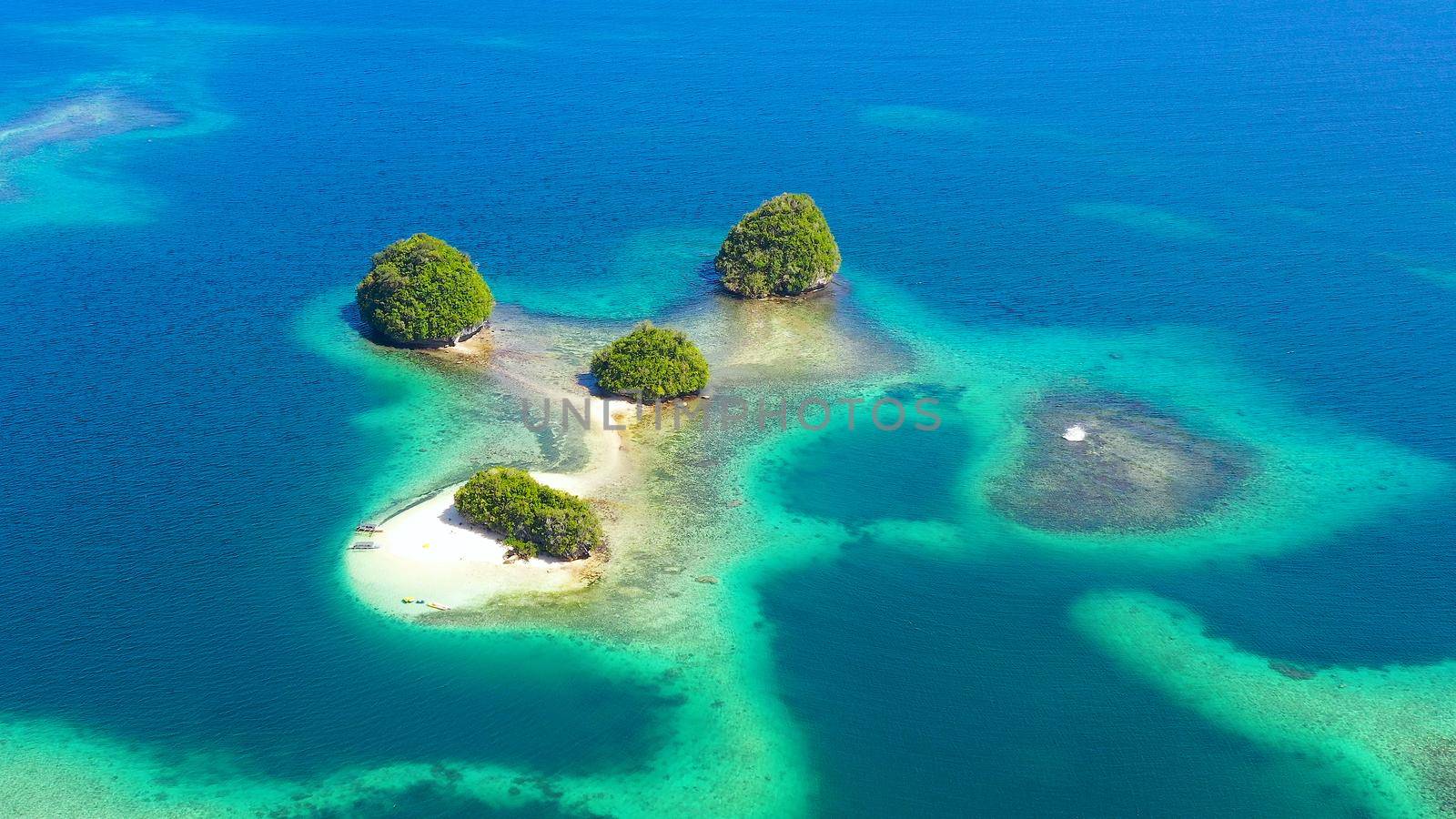 Top view of small tropical island in the blue sea with a coral reef and the beach. Britania Islands, Surigao del Sur, Philippines.
