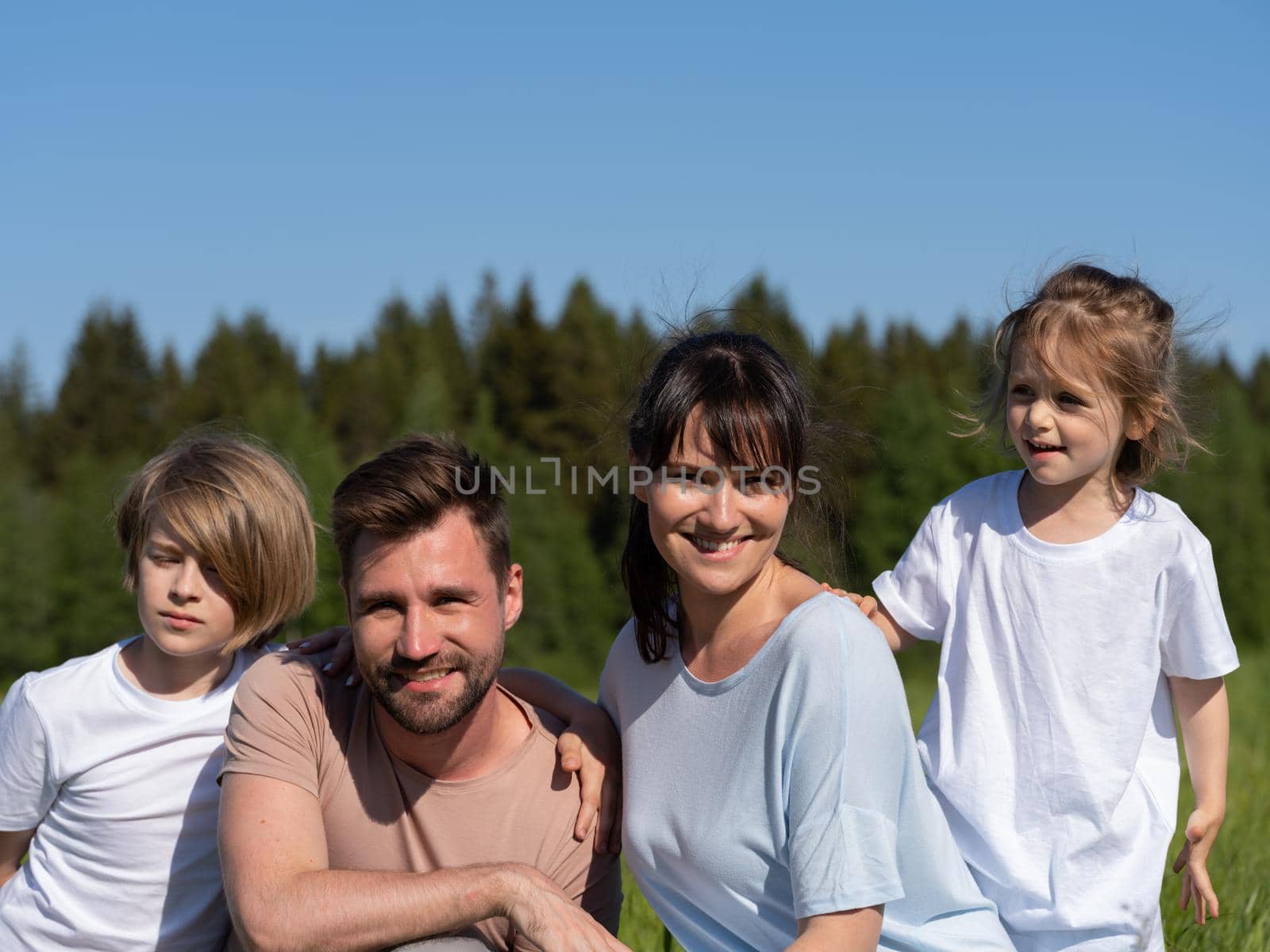 Happy smiling family: man, woman and kids having fun outdoors against blue sky background. Summer vacations concept