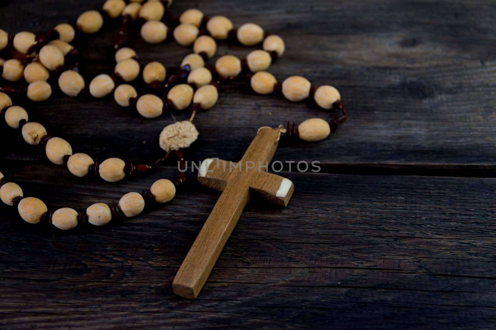 detail of the cross of a catholic rosary on rustic wood