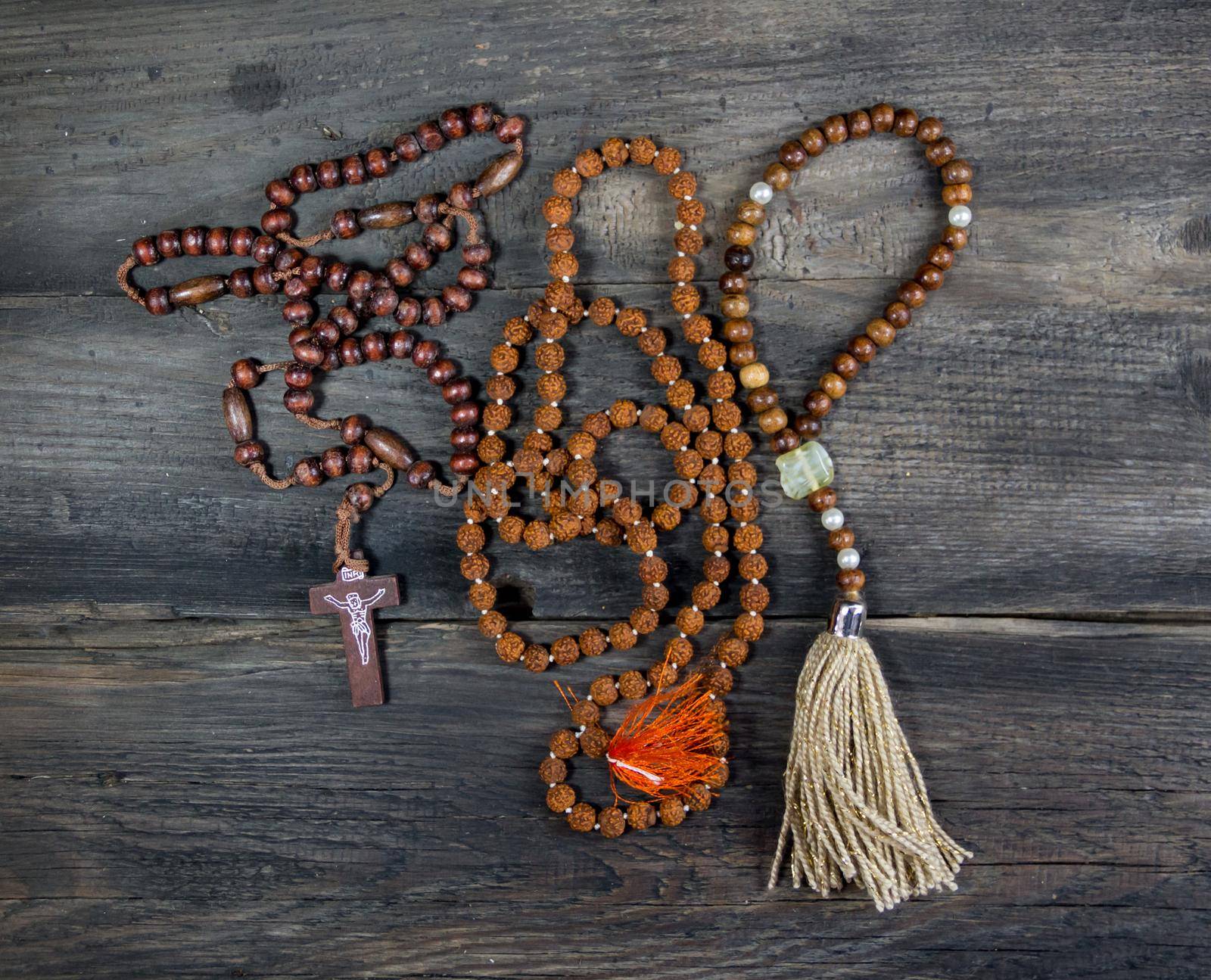 set of rosaries of various religions on rustic wood by GabrielaBertolini