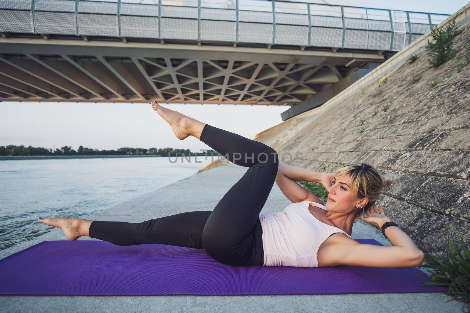 Woman exercising outdoor. She is practicing sit-ups.