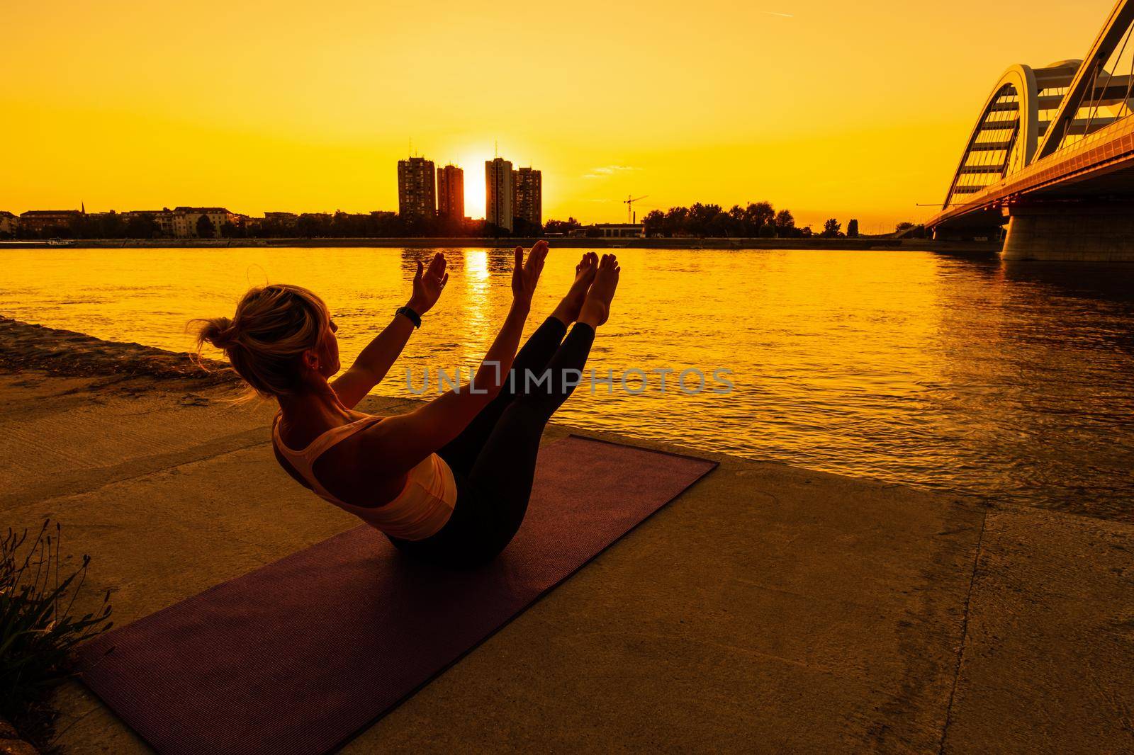 Woman exercising pilates on sunny day. Teaser exercise.