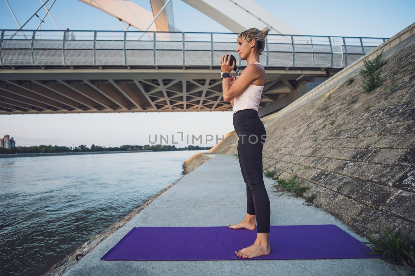 Woman exercising kettlebell pilates outdoor.