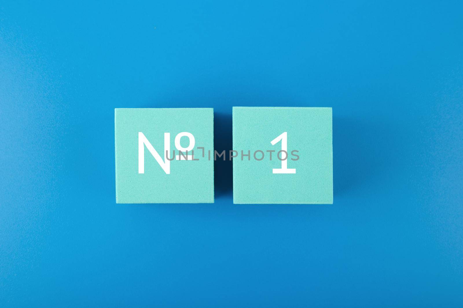 Number 1 written on light blue cubes against dark blue background. Concept of being first, best selling or award winner