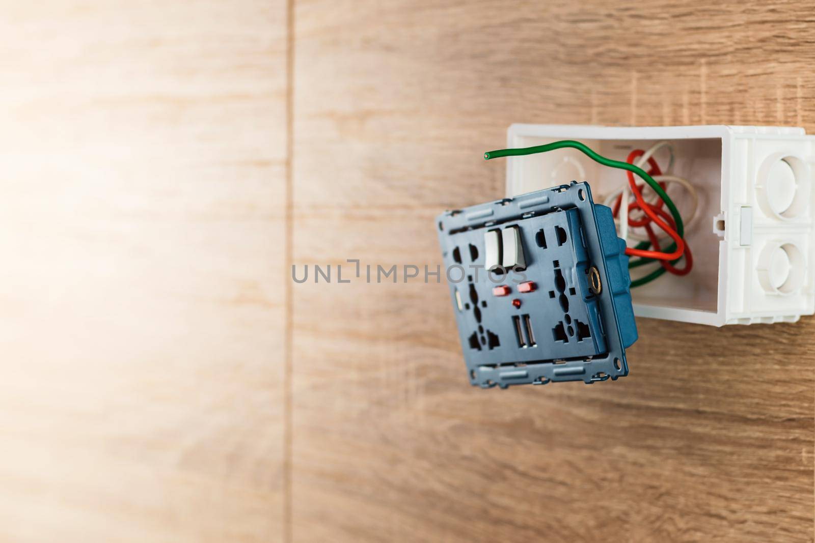 Universal wall outlet AC power plug with USB port in a plastic box on a wooden wall.