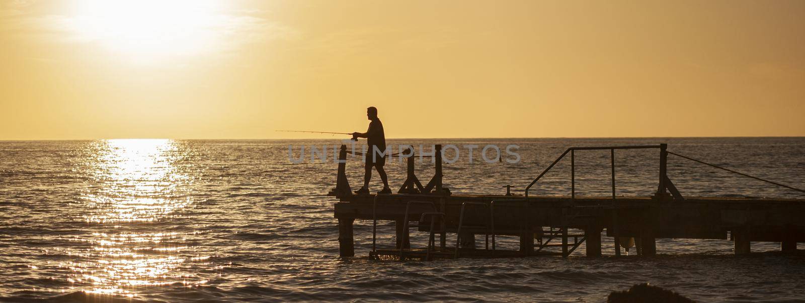 Fisherman on the pier at sunset, banner image with copy space