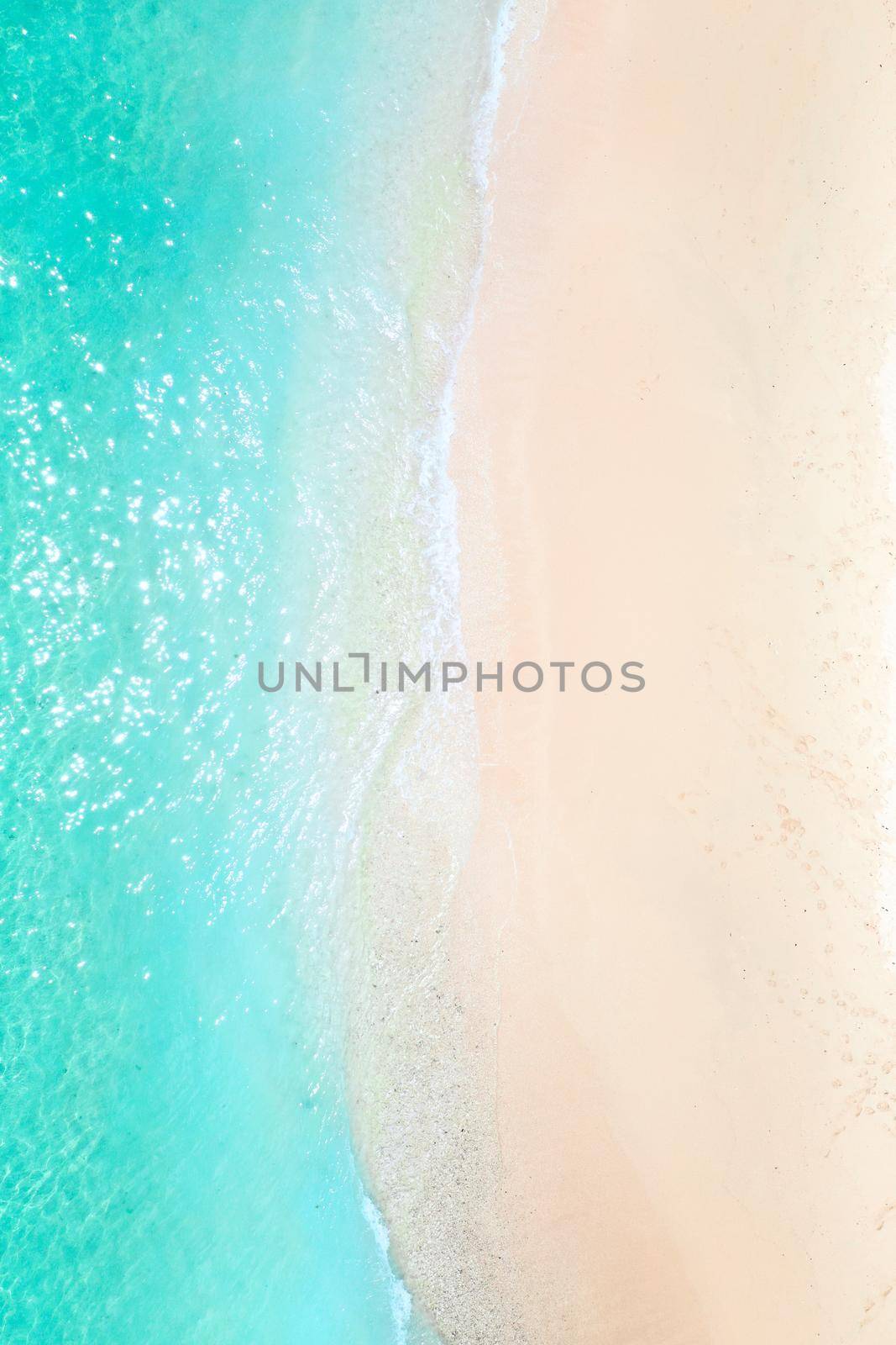 A view from a height of a Tropical beach and waves breaking on a tropical golden sandy beach. The sea waves gently wind along the beautiful sandy beach.