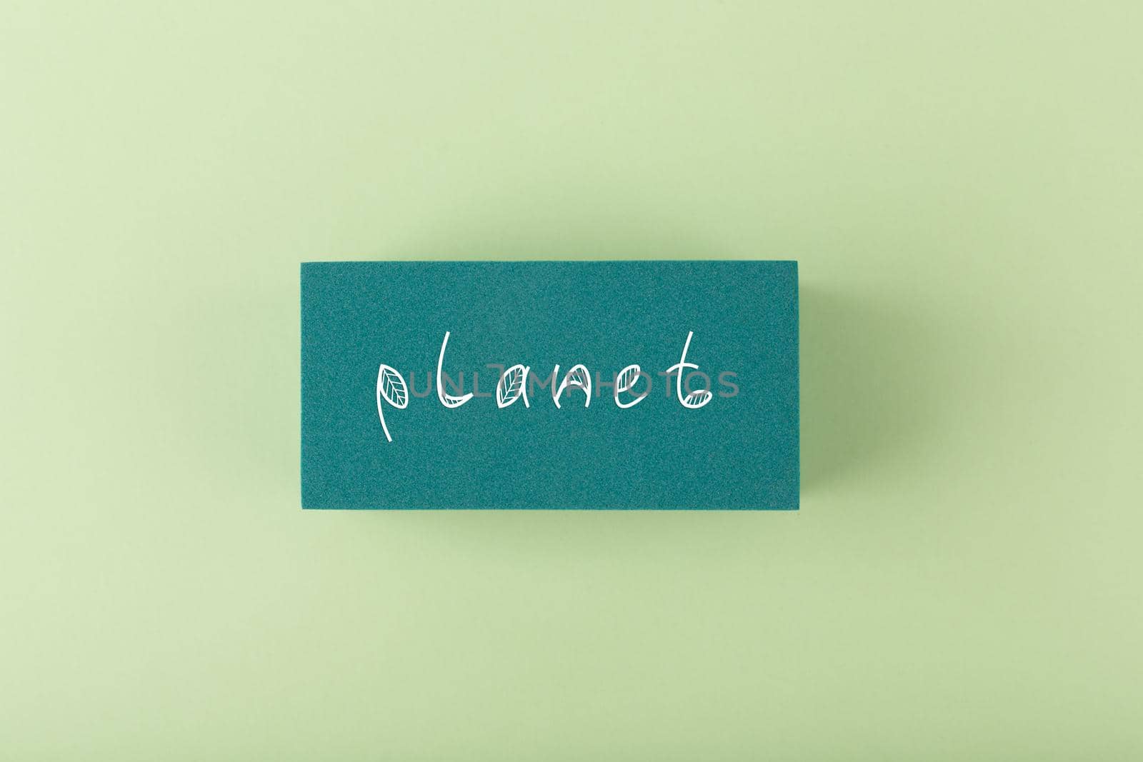 Planet handwritten on dark green rectangle against light green background. Concept of planet, eco friendly life style, plastic, pollution or ecological problems