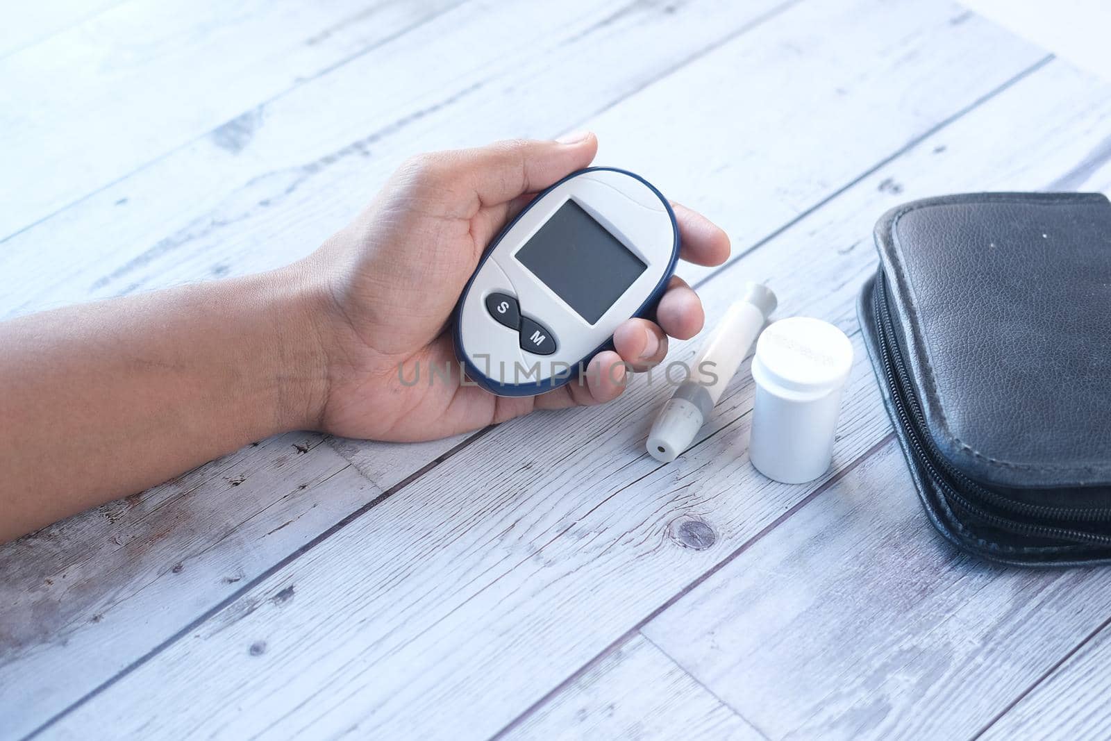 Rear view of hand hold a diabetic measurement tools on table by towfiq007