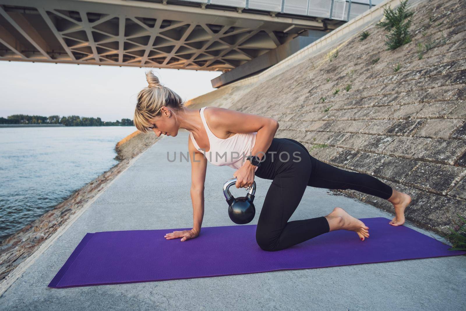 Woman exercising kettlebell pilates outdoor.