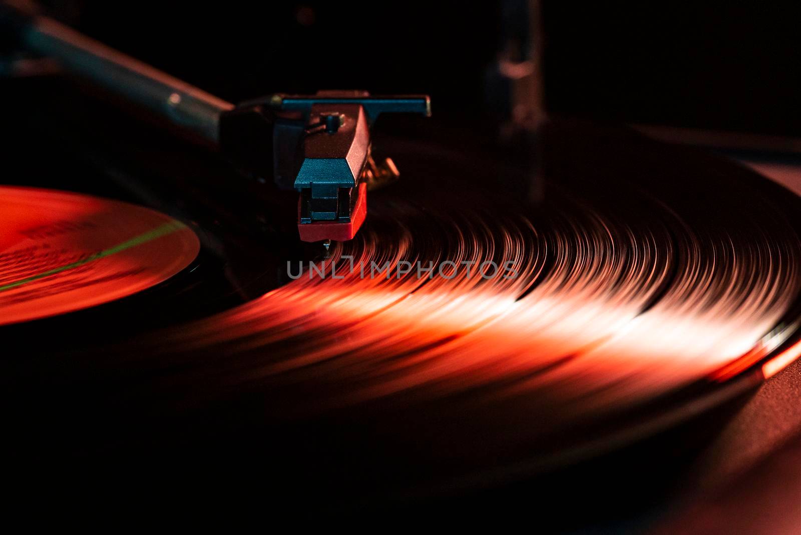 Needle detail on vinyl record on turntable, low light image with reflection