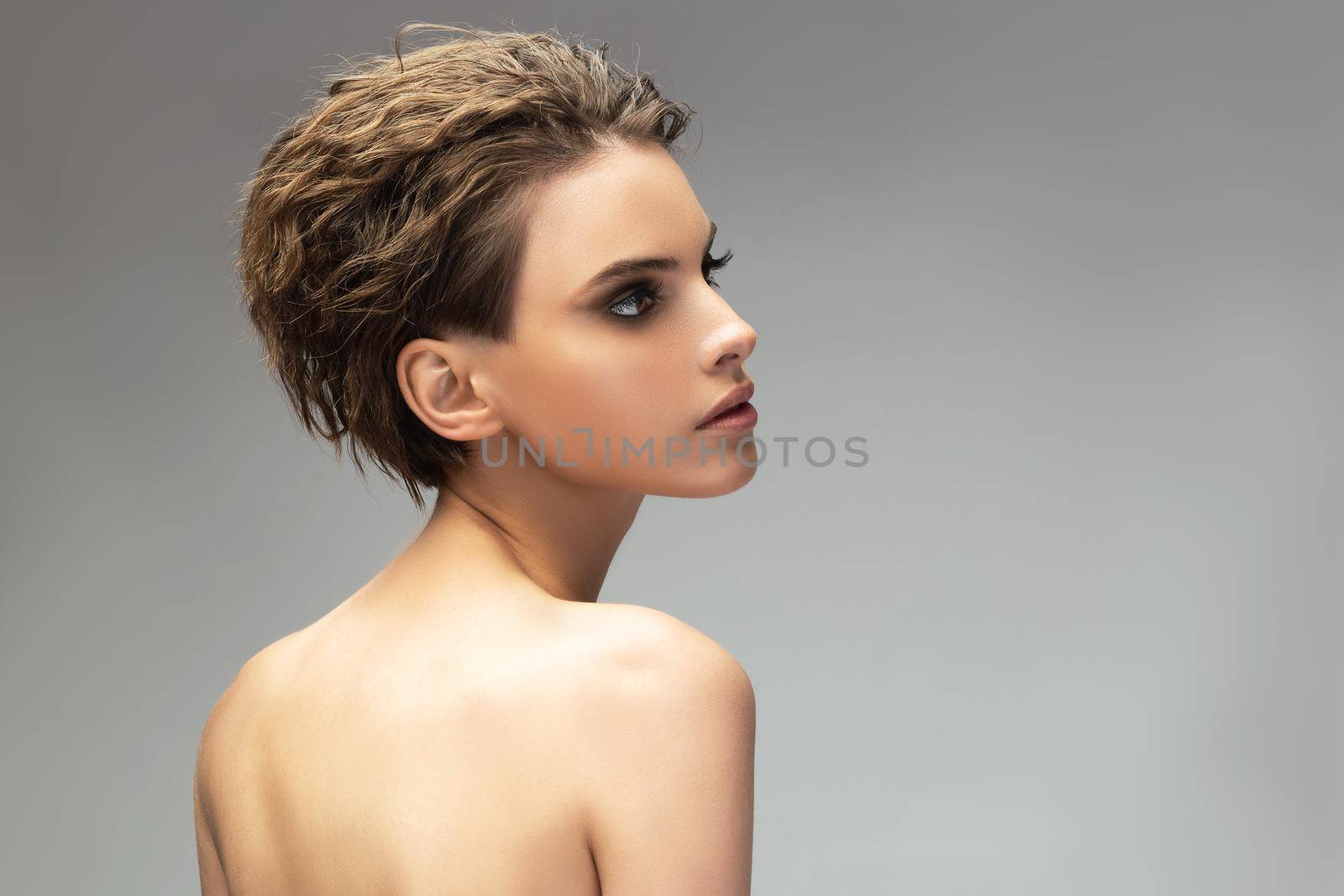 Glamorous portrait of young woman on gray background. Young sensual model girl pose in studio.