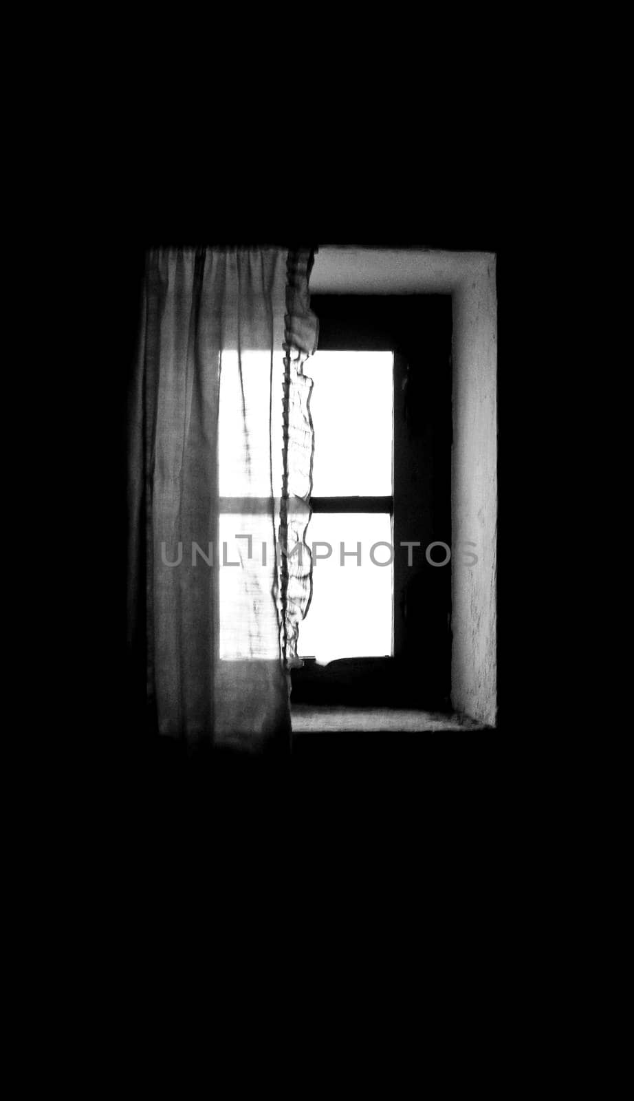 Window of old house with white curtain in Spain. Monochrome picture.