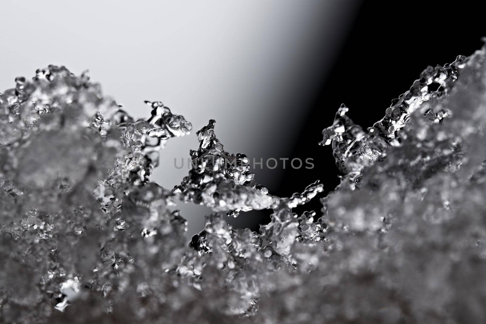 Thawing snow or frost, super macro close up image with an abstract background. Selective focus and soft black and white background. Microscopic detail