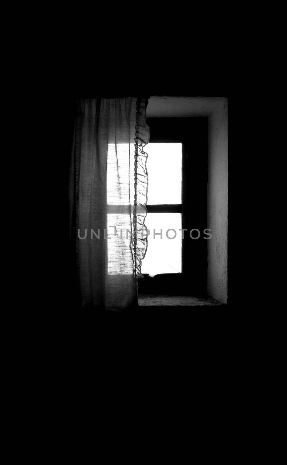 Window of old house with white curtain in Spain. Monochrome picture.