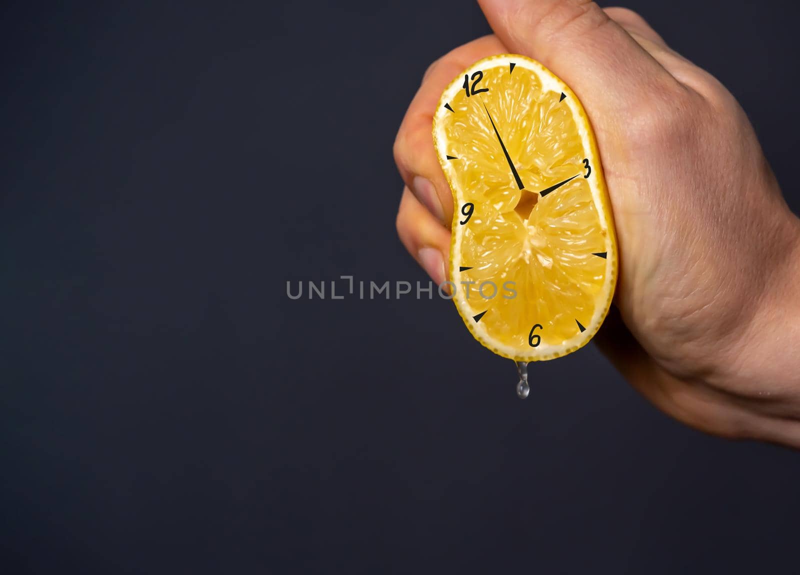 Hand squeezes out a lemon, on which the clock is drawn. Creative hours as a symbol of wasted time, overwork and poor planning. Nutritious citrus as benefits, a person's contribution to their health.