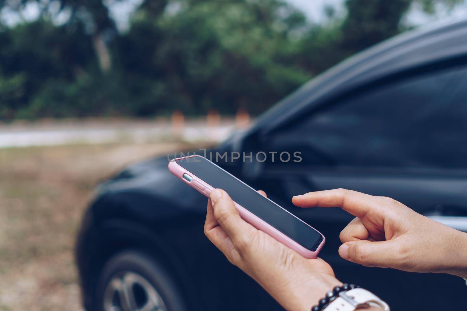 Woman hand using smartphone to do work business, social network, communication in front of car background.