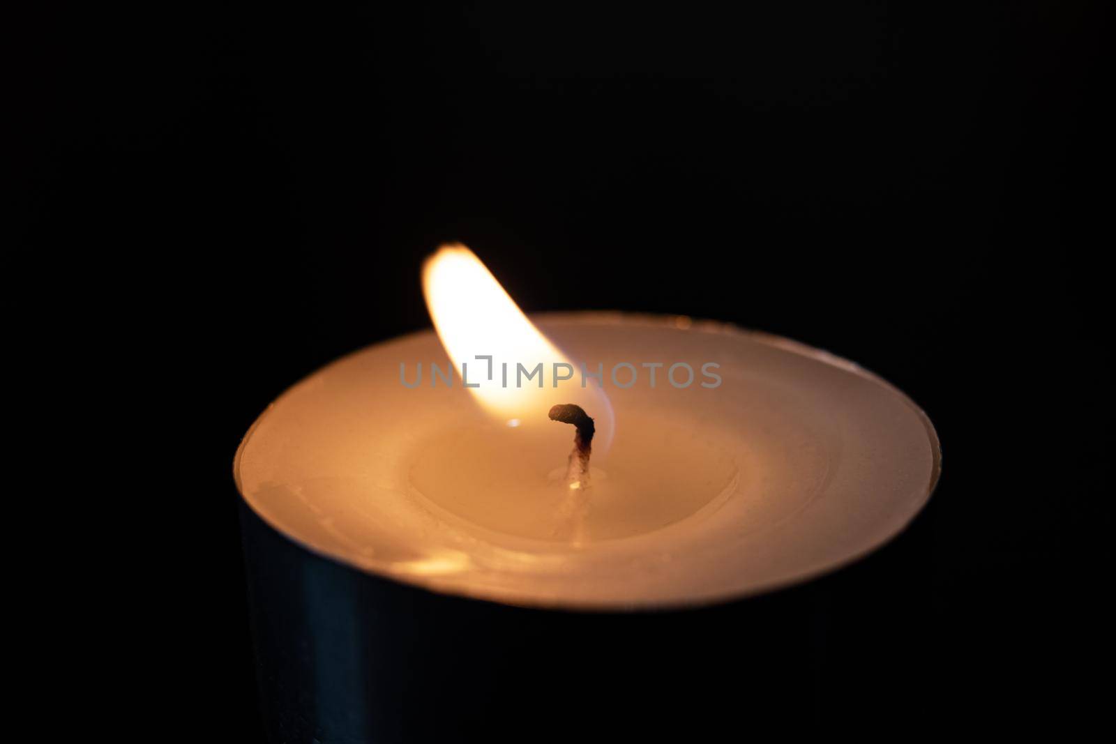 Flame of a small candle in the dark close up